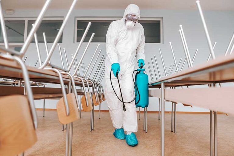 Cleaning specialist spraying throughout a classroom